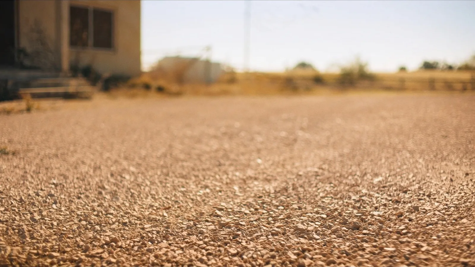 Fresh crushed-limestone residential driveway with country house in background.