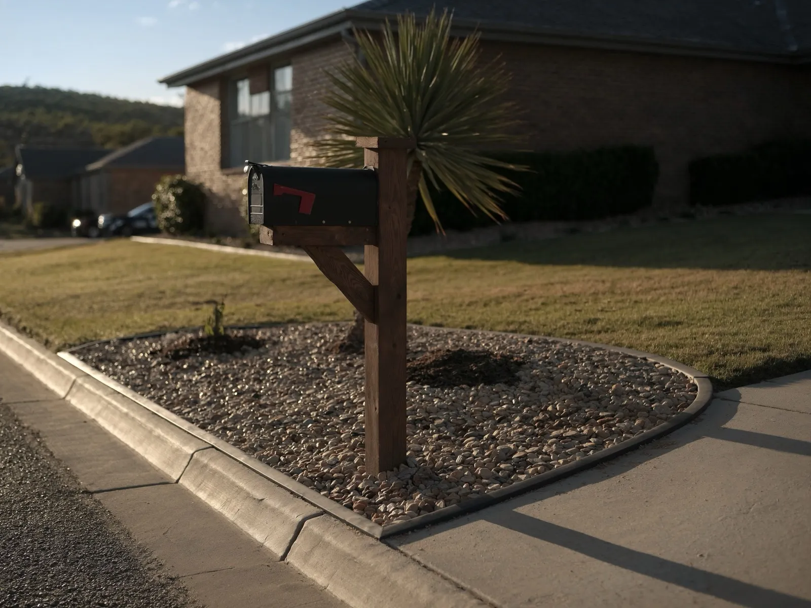 Mailbox post with a tidy decorative bed of Sabine river rock and a yucca, suburban Texas curb view