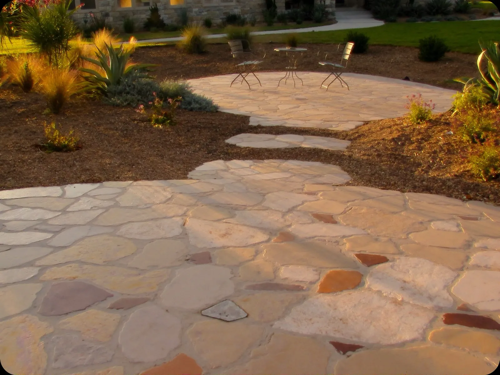 Hand-fit Oklahoma multi-color flagstone patio in a residential backyard with a bistro set and native plant border